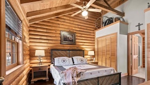 A log cabin-style bedroom with a bed, two bedside tables, a ceiling fan, and a framed picture on the wall. - Private Cabin with Whirlpool Tubs, Free Wifi, 150 Beautiful Acres (Branson)