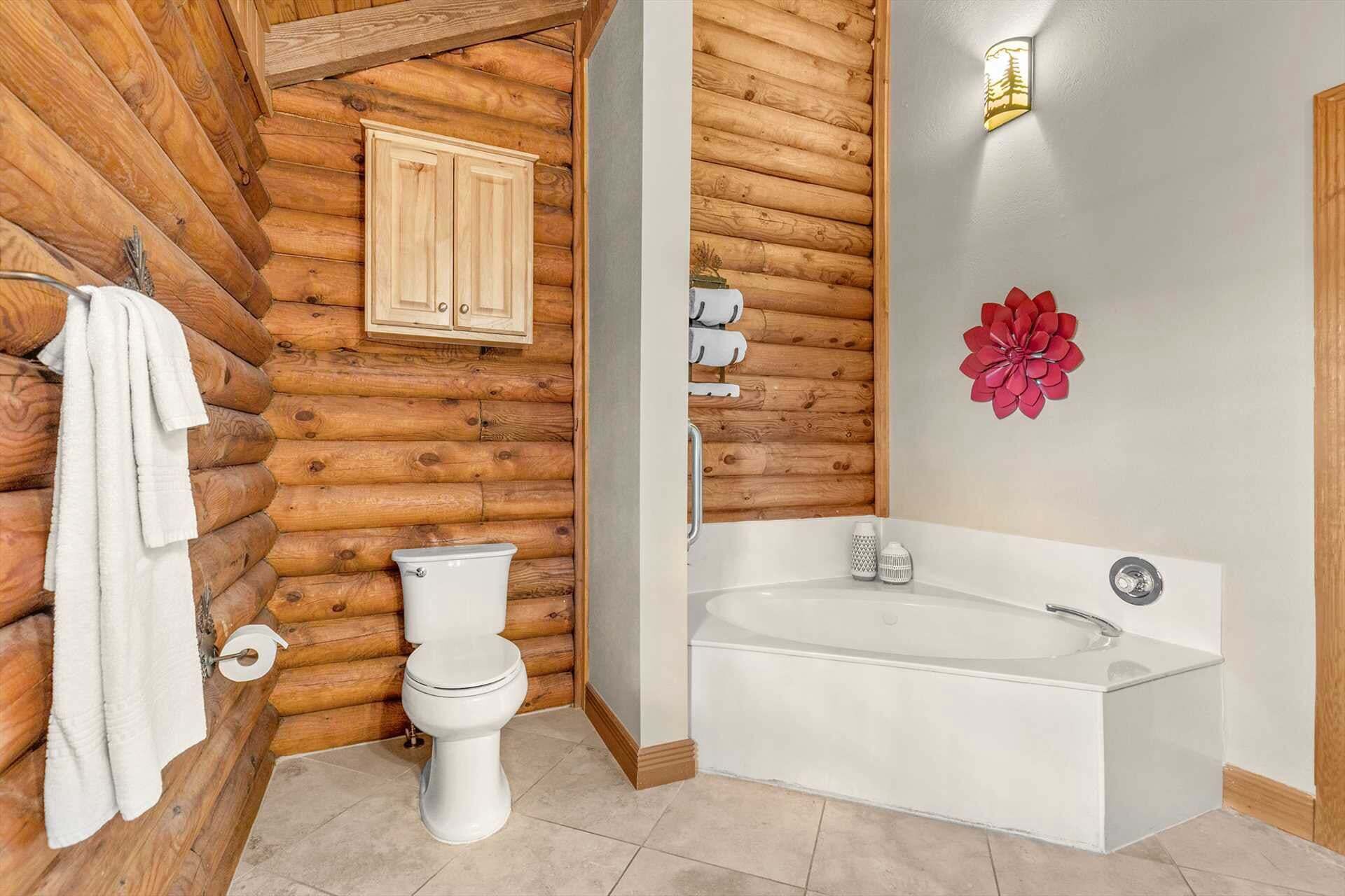 Un bagno con parete in legno a tronchi, un water bianco, una vasca da bagno e una decorazione floreale rossa.
