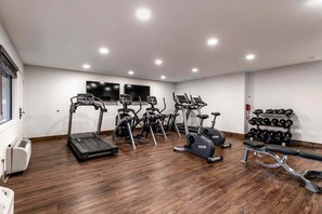 Et fitnesscenter med løbebånd, crosstrainere og bænkpres.