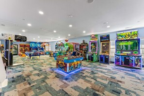 A room with arcade games, a carpeted floor, and a ceiling with recessed lighting.