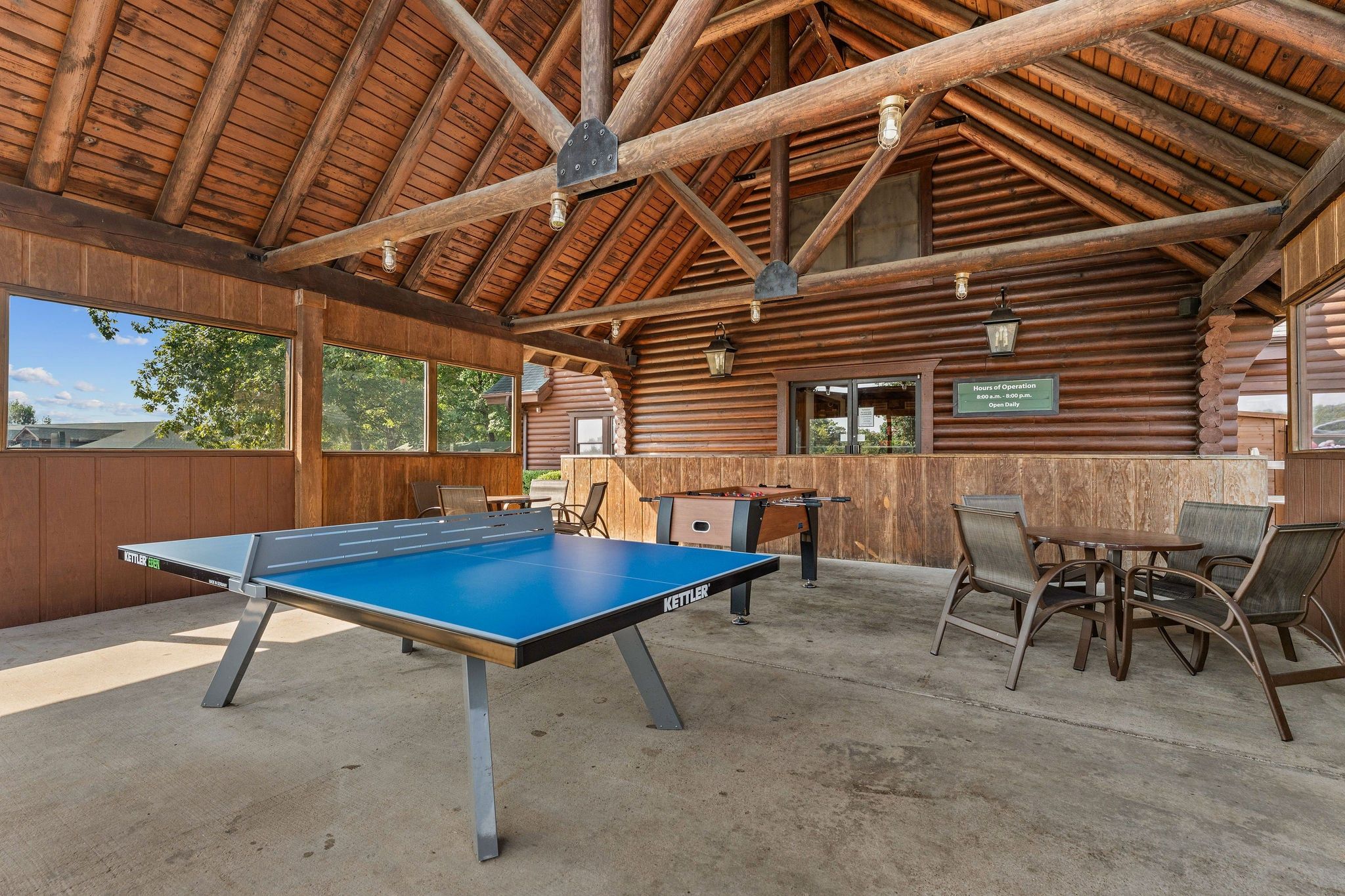 Un espace de loisirs intérieur comprenant une table de baby-foot, une table de ping-pong et un coin salon.