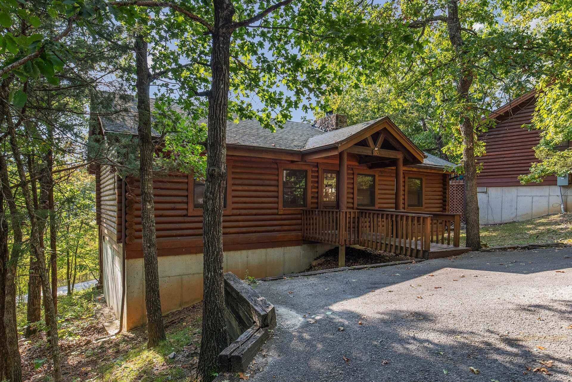 Une cabane en bois avec un porche, entourée d’arbres.