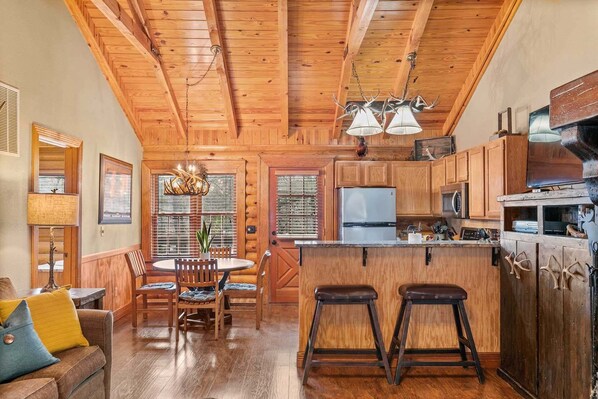 A wooden interior with a dining area, kitchen, and bar stools.