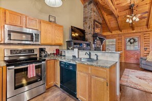 A kitchen with wooden cabinets, stainless steel appliances, and a stone fireplace.