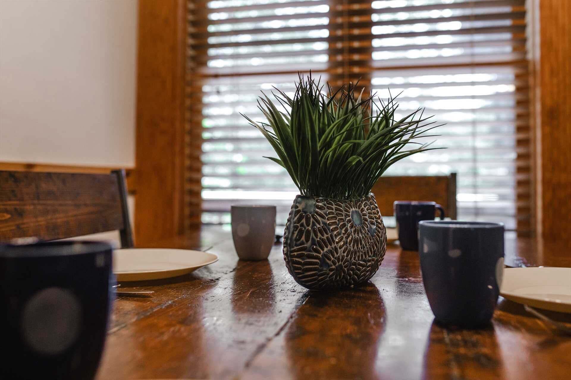 A dining table with a decorative plant centerpiece, a coffee cup, and a plate.