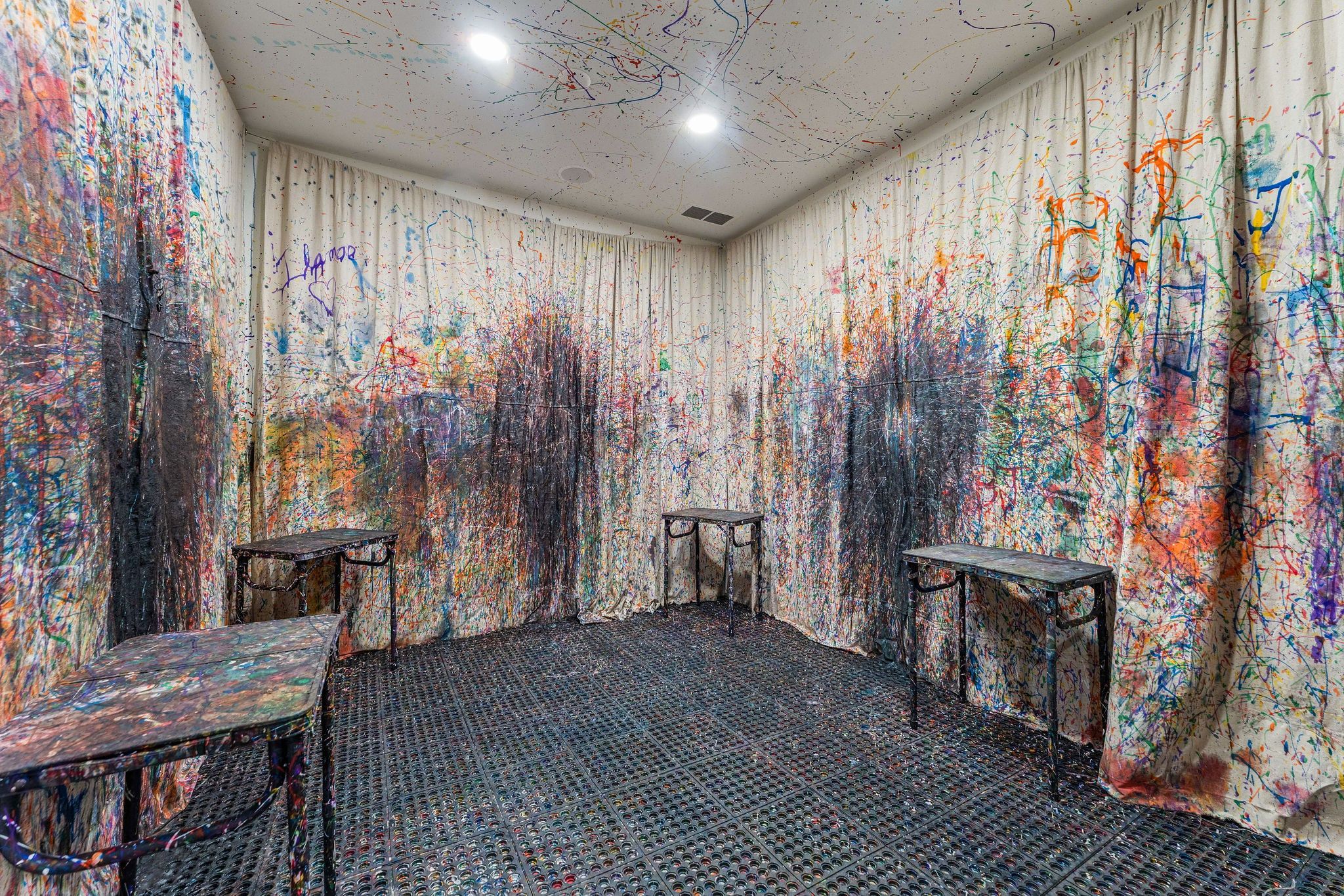 A room with a floor covered in circular objects, two tables, and walls with colorful abstract patterns.