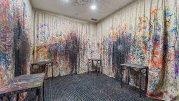 A room with a floor covered in circular objects, two tables, and walls with colorful abstract patterns.