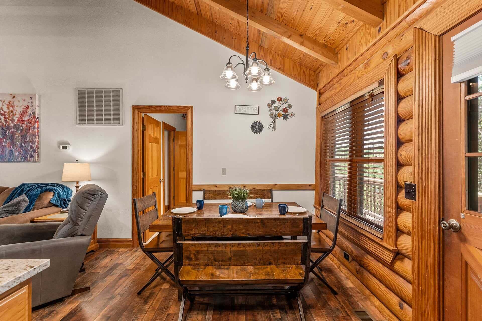 A cozy dining area with a wooden table, chairs, and a hanging light fixture.