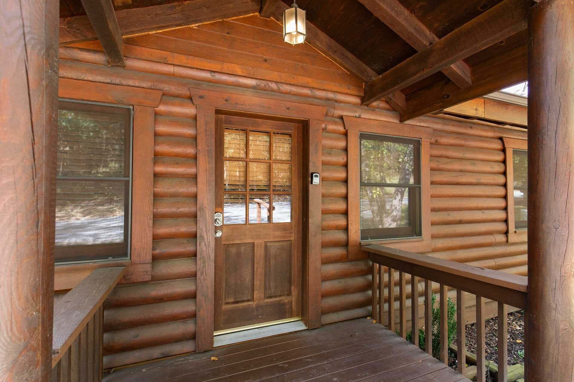 Una baita di legno con una porta d'ingresso in legno, finestre e un portico con ringhiera.