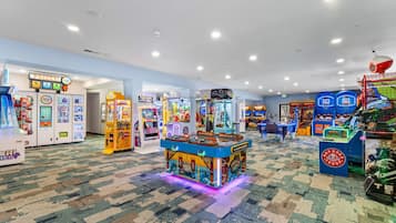 A brightly lit arcade area with various gaming machines and a prize hub.