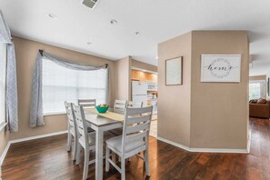 A dining area with a table and chairs, a kitchen in the background, and a living room with a couch. - Cozy Condo_ Free Daily Attraction Tickets_ Close to Branson (Branson)