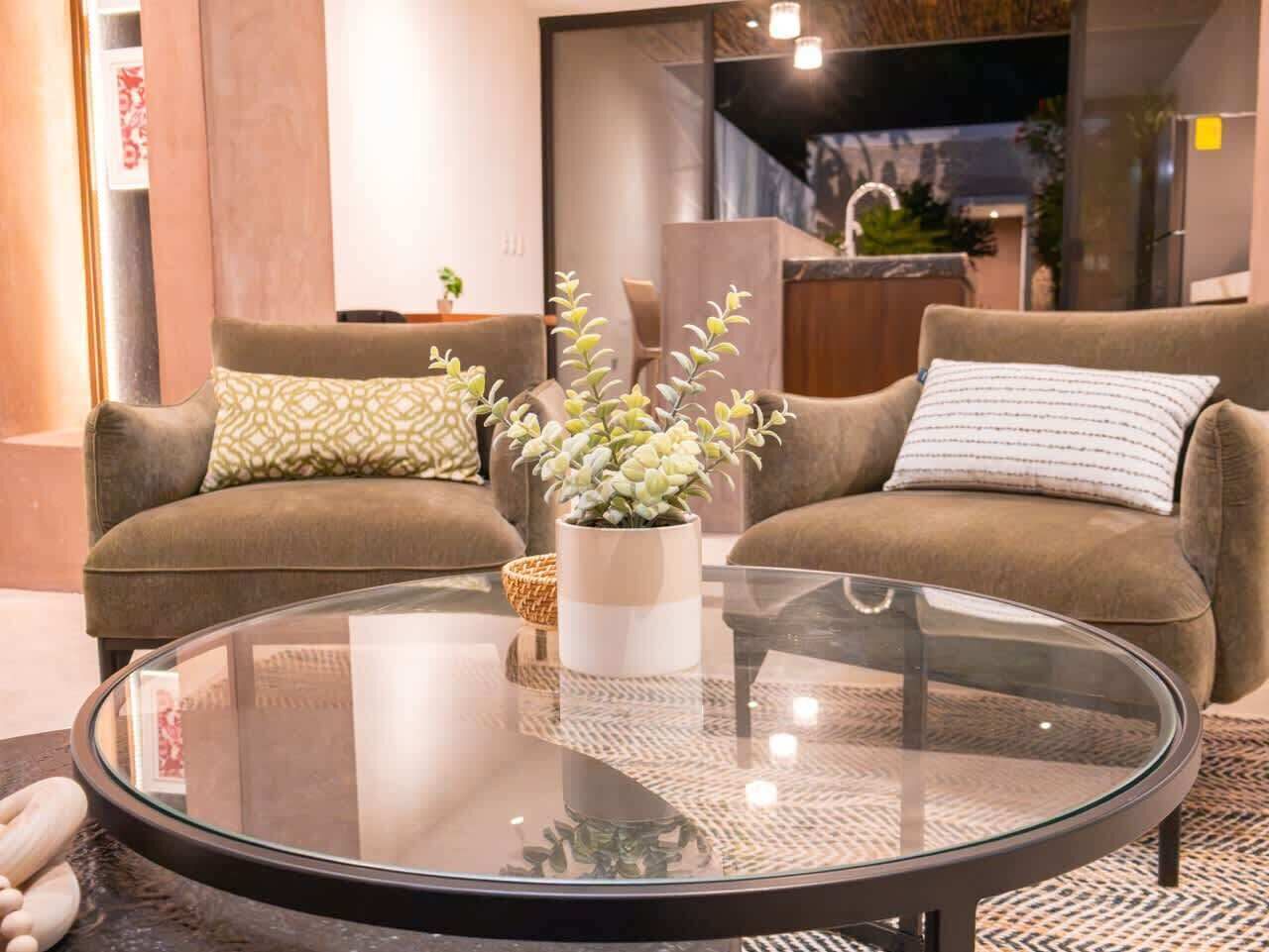 Een woonkamer met een ronde glazen salontafel, twee banken en een kamerplant.