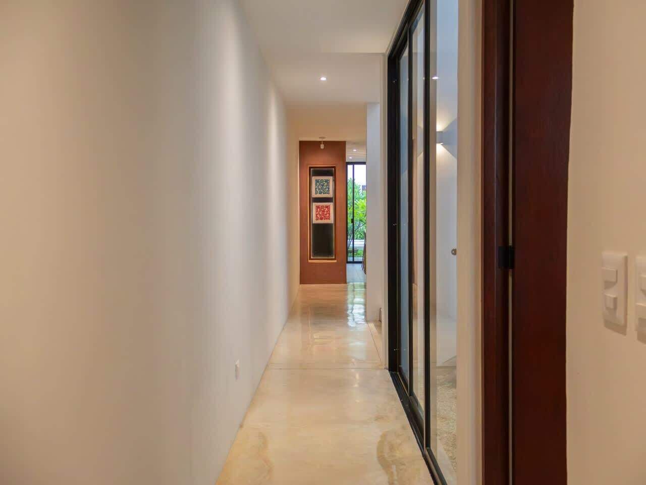 Un pasillo con una puerta a la derecha, un cuadro en la pared y otra puerta al final.