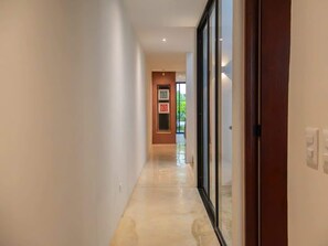A hallway with a door on the right, a framed picture on the wall, and a door at the end. - Private Pool Near Centro, Montejo & Zoo | 2BR (Mérida)