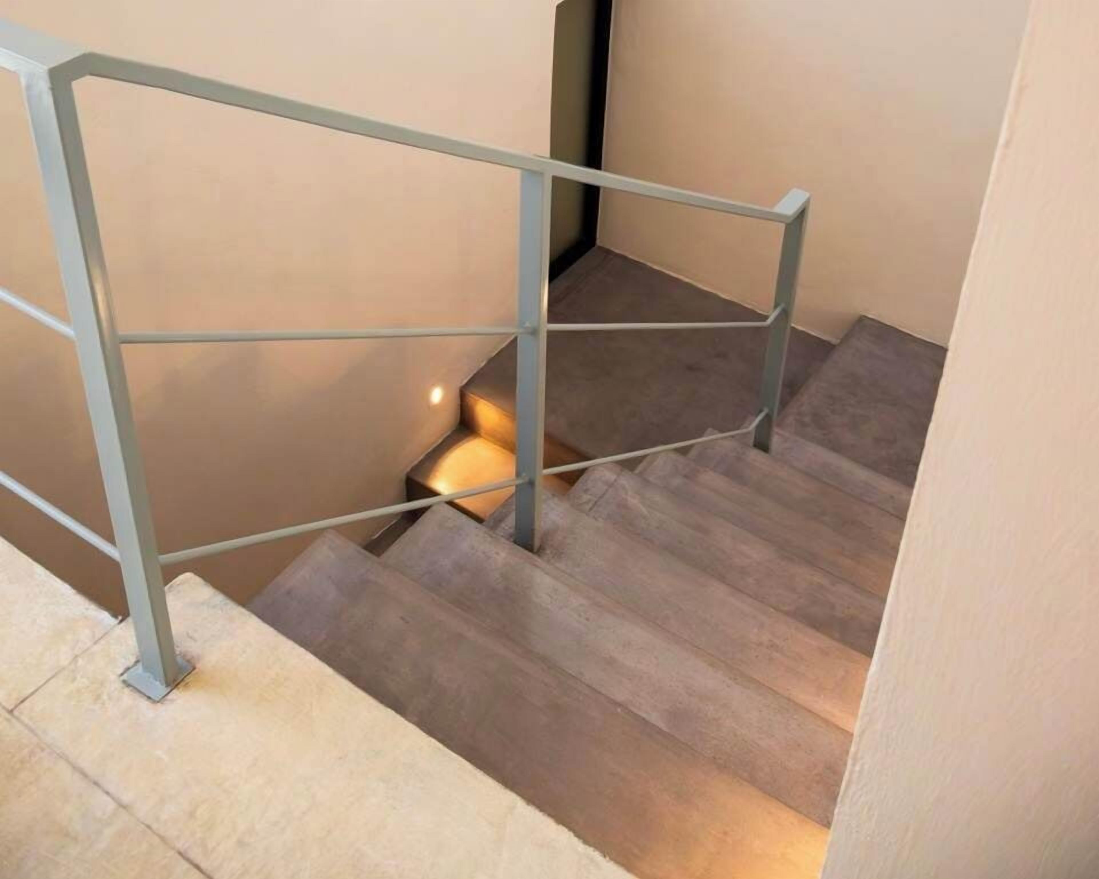 Una escalera con barandilla de metal y peldaños de madera.