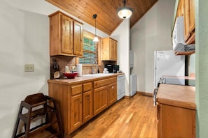 A compact kitchen with wooden cabinets, a built-in dishwasher, and a refrigerator.