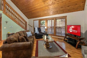 A living room with a wooden ceiling, a television, and a staircase. - Beautiful Lodge near SDC, Private Fishing Lake, Free Daily Attraction Tickets (Branson West)