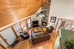 A spacious living room with a fireplace, wooden ceiling, and a stone accent wall.