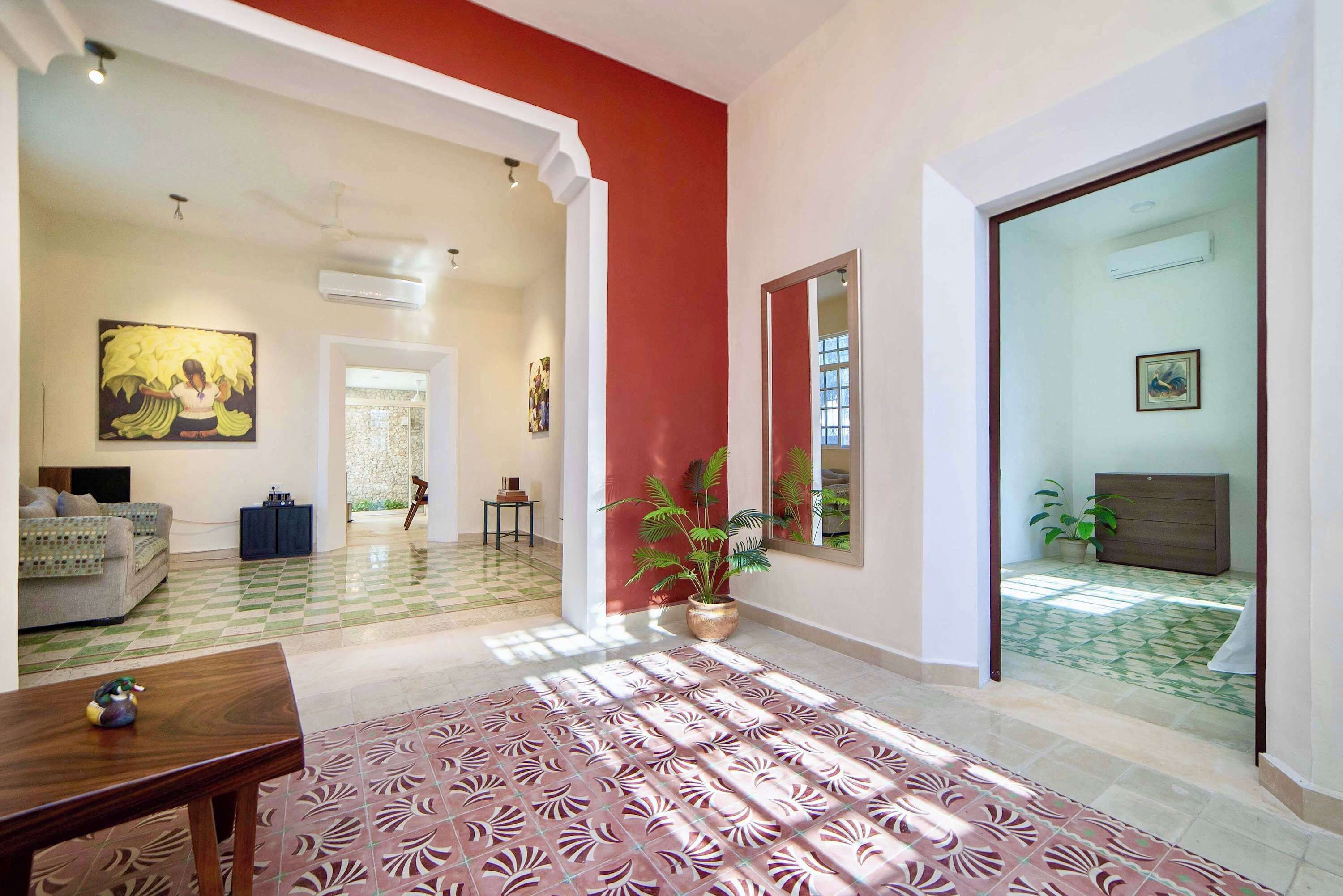 A spacious living area with a checkered floor, a large window, and a red accent wall.