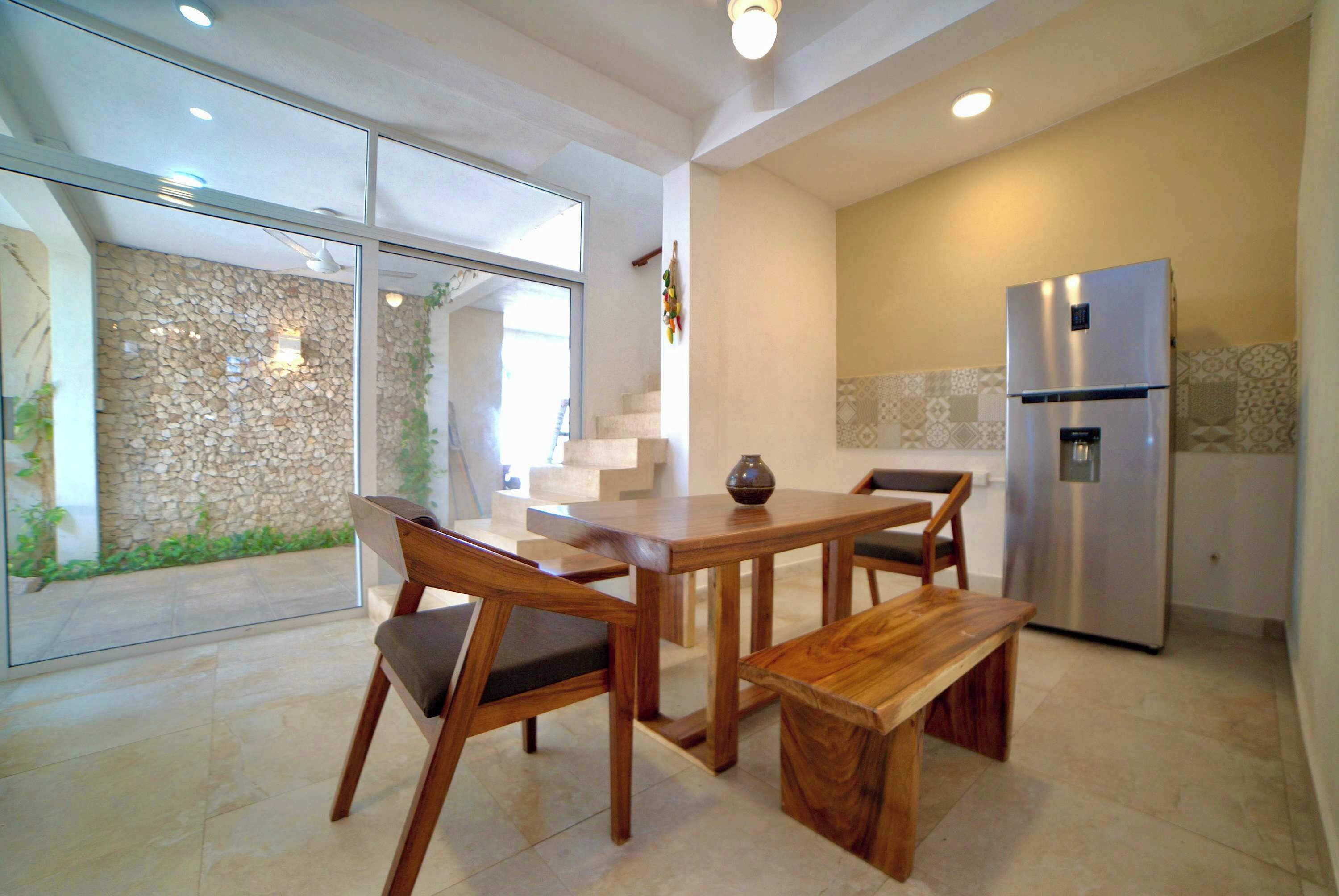 A modern kitchen with a built-in stainless steel refrigerator, wooden dining table, and chairs.