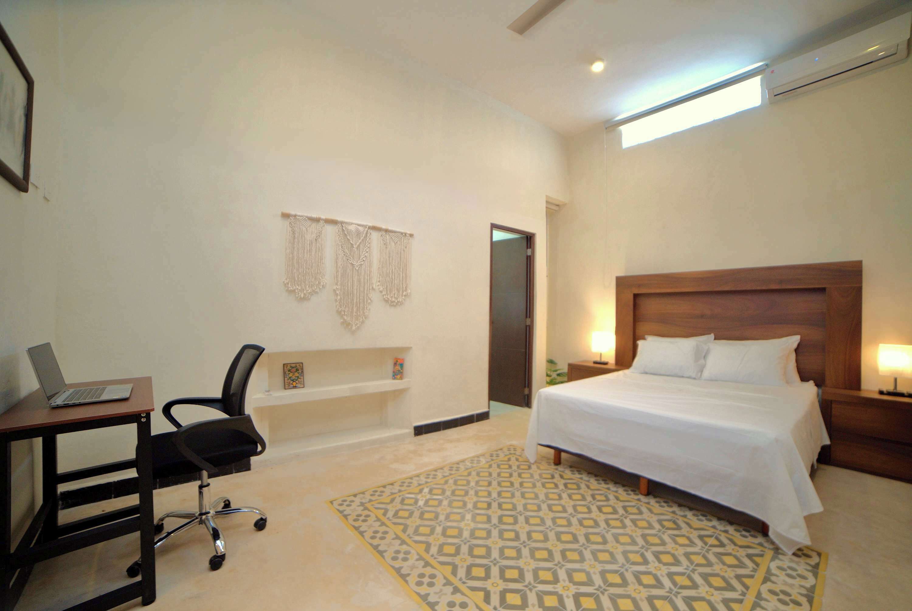 Habitación de hotel con cama, escritorio, silla y una alfombra estampada.