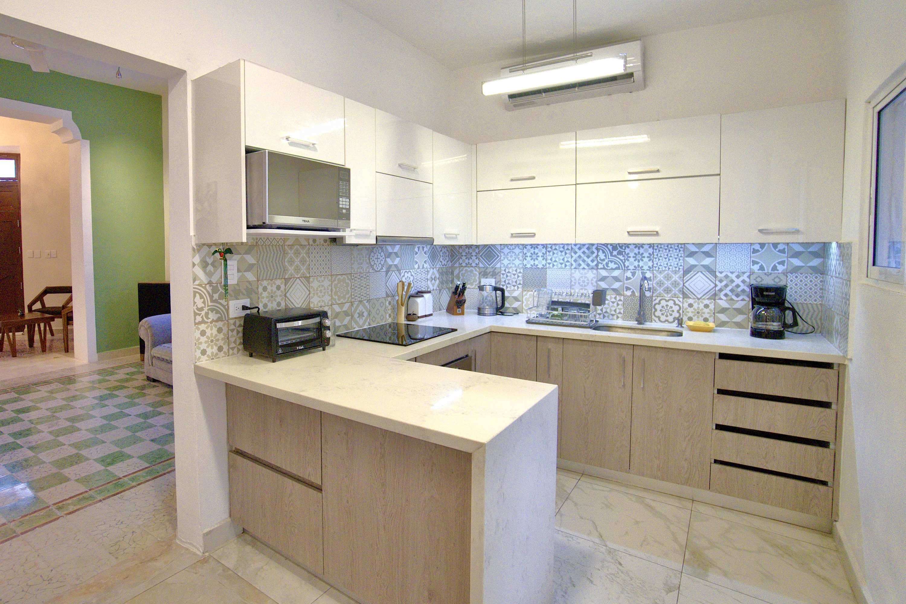 Una cocina moderna con armarios blancos, un microondas, un tostador y una cafetera.