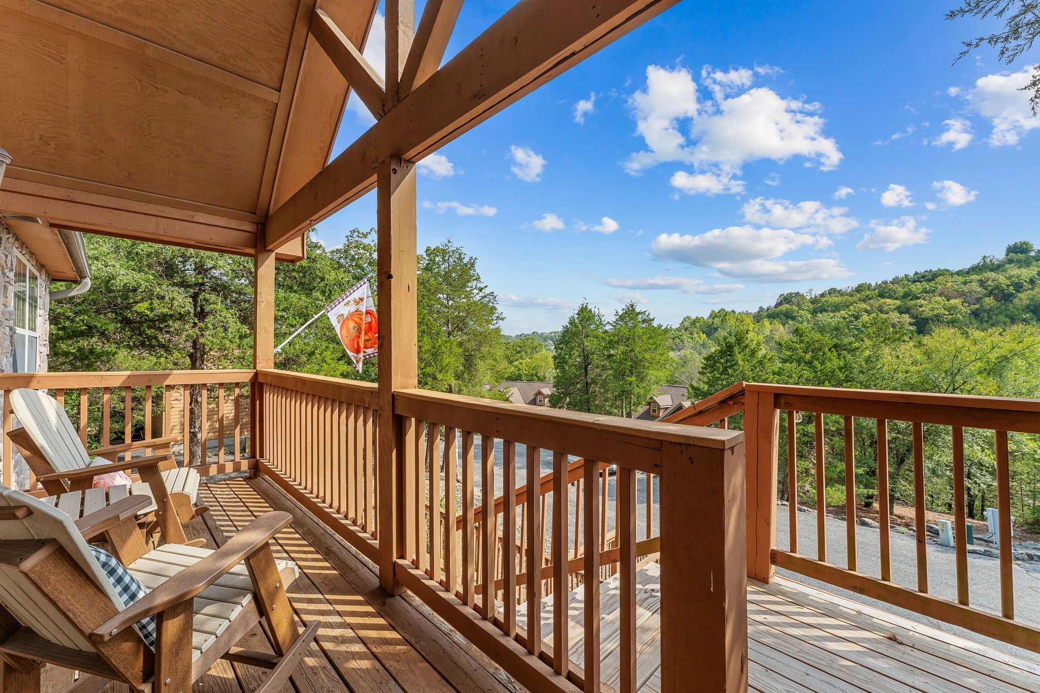A wooden deck with a view of a forested area and a river.