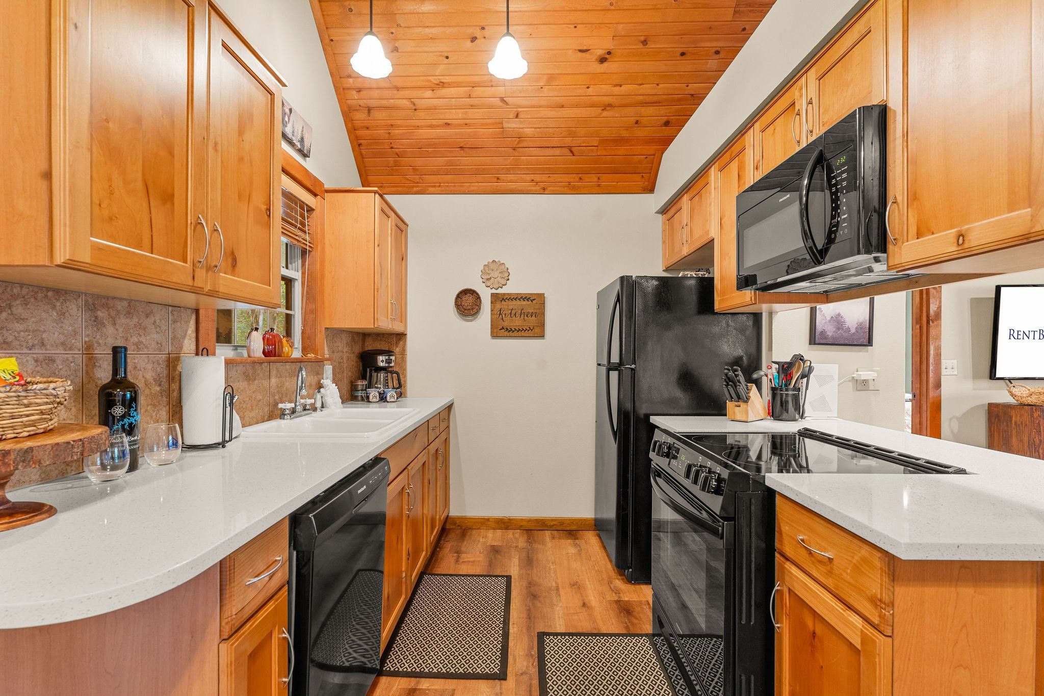 A kitchen with wooden cabinets, a black refrigerator, a stove, and a microwave.