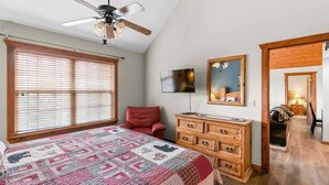 Une chambre à coucher comprenant un lit, une commode, un téléviseur et un ventilateur de plafond.
