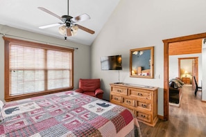 A bedroom with a bed, a dresser, a television, and a ceiling fan. - Pet Friendly Lodge Near Silver Dollar City w Onsite Golf Course (Branson West)