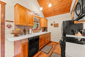 A kitchen with wooden cabinets, a black refrigerator, and a coffee maker.