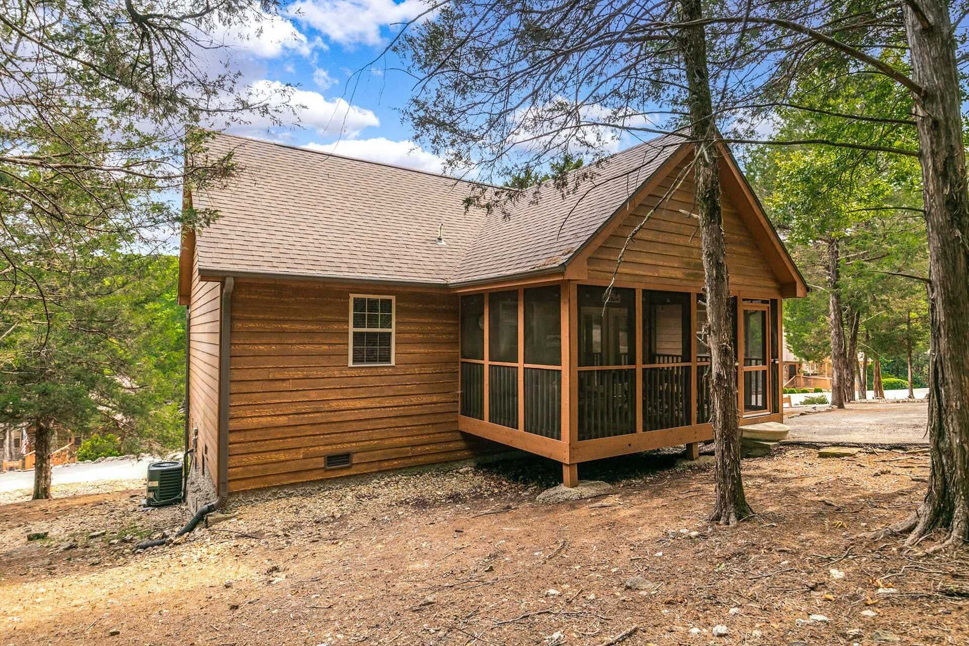 Une cabane en bois avec un toit en pente, de grandes fenêtres et une véranda.