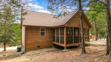 Une cabane en bois avec un toit en pente, de grandes fenêtres et une véranda.