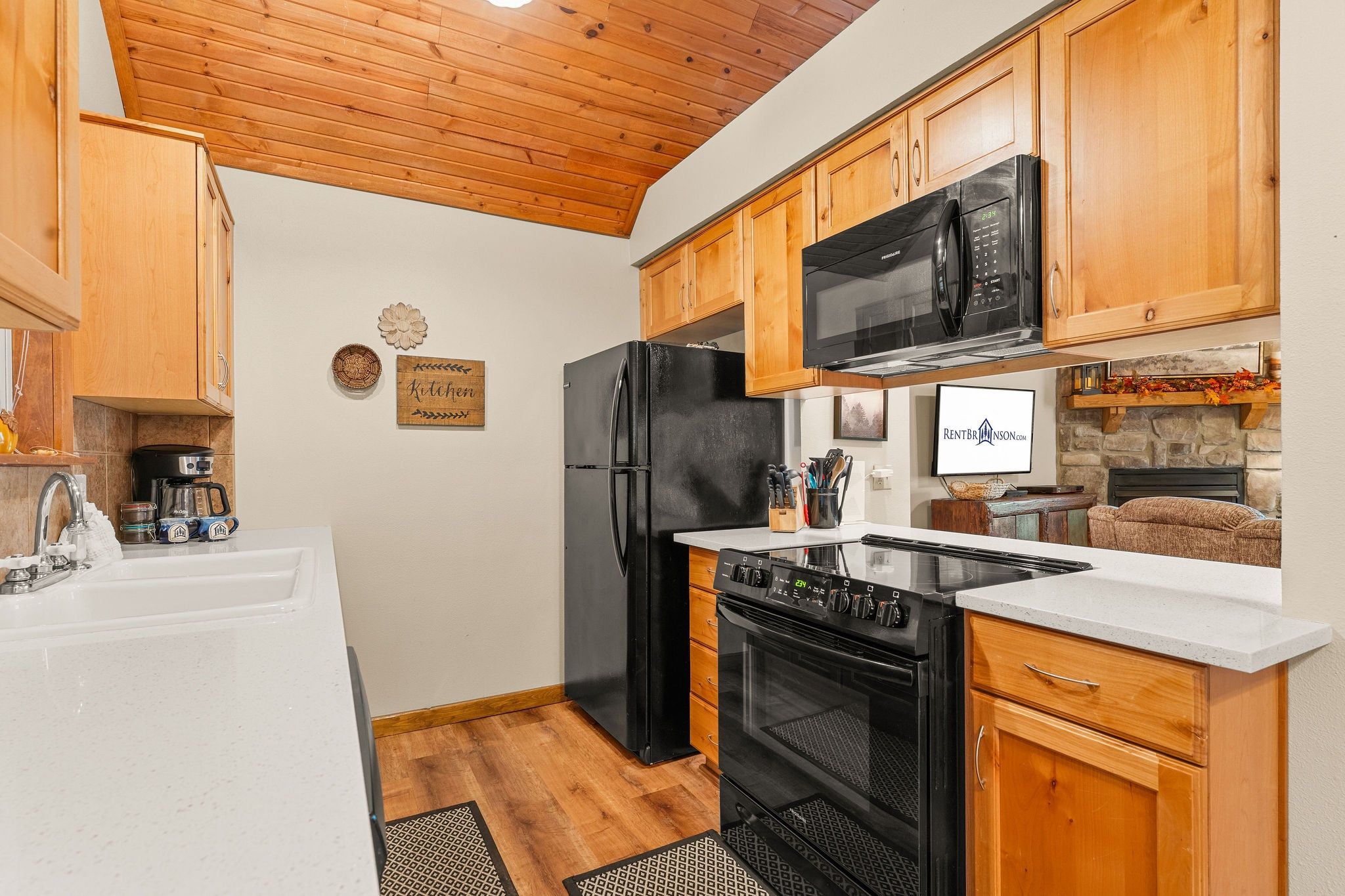 A kitchen with wooden cabinets, a black refrigerator, a microwave, and a stove.