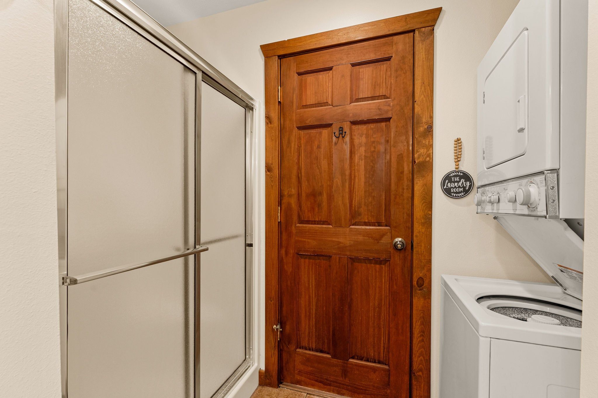 A laundry room with a wooden door, a washing machine, and a dryer.