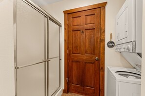 A laundry room with a wooden door, a washing machine, and a dryer.