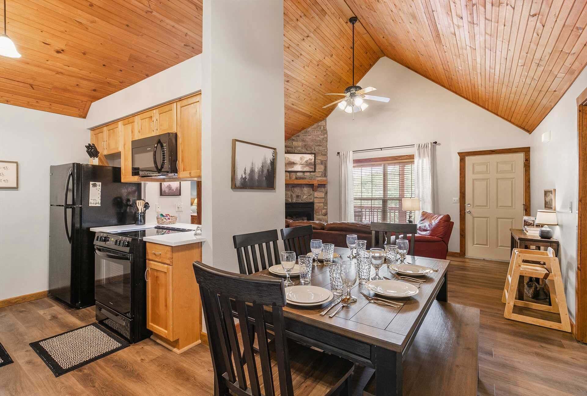 A spacious kitchen with wooden cabinets, a black refrigerator, and a dining area with a wooden table set for four.