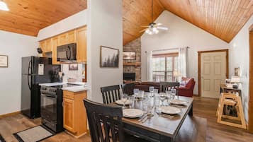 A spacious kitchen with wooden cabinets, a black refrigerator, and a dining area with a wooden table set for four.