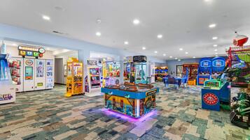 Une zone d’arcade bien éclairée, avec différents jeux et un espace dédié aux prix à gagner.
