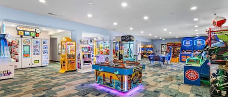 A brightly lit arcade area with various gaming machines and a prize hub.