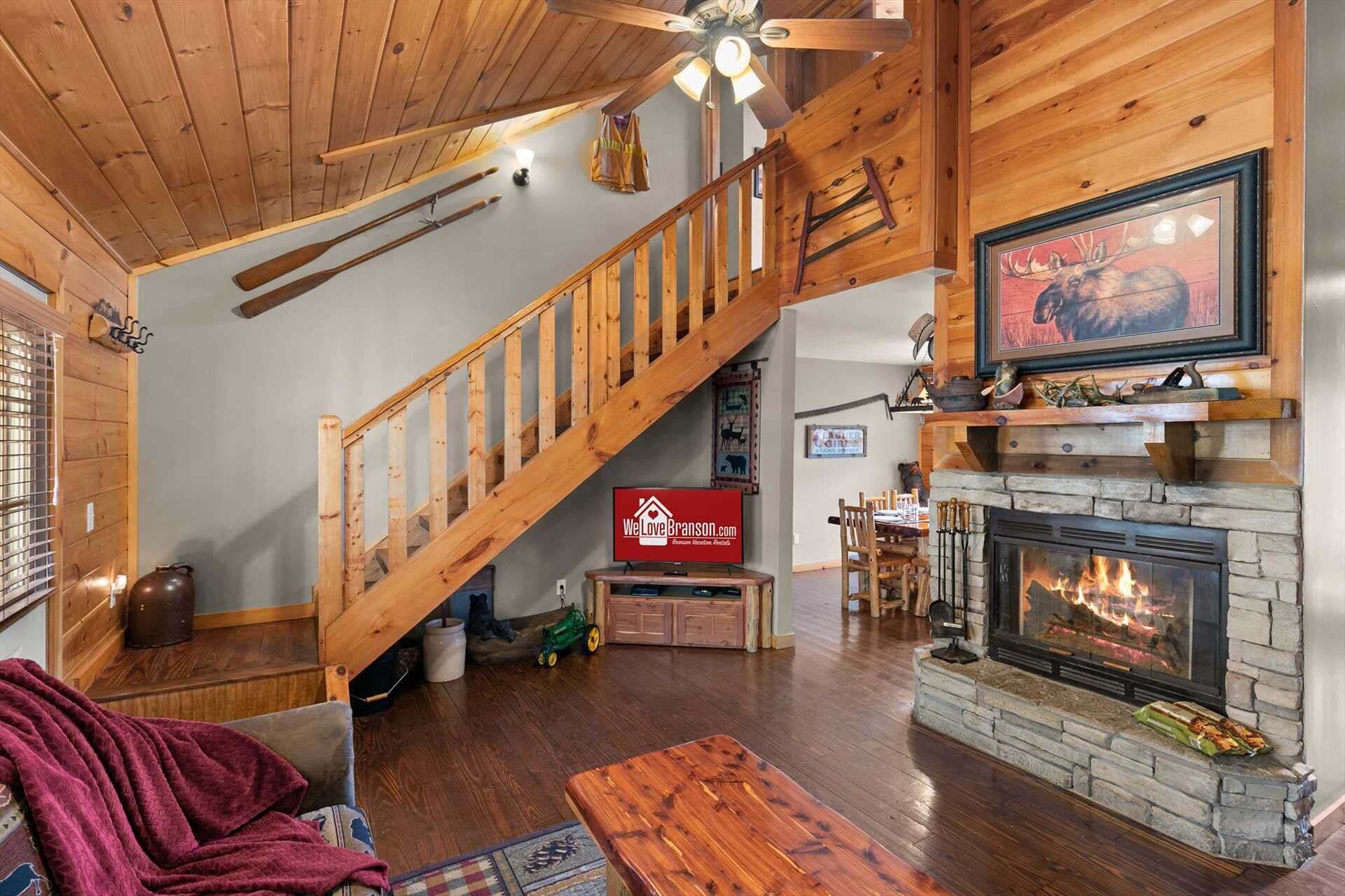 Un vaste salon doté d’un escalier en bois, d’une cheminée et d’un téléviseur fixé au mur.