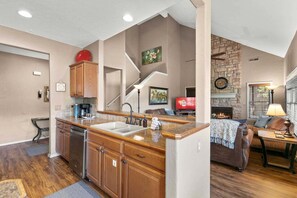 A kitchen with wooden cabinets, a built-in stove, and a dining area with a couch and table. - Beautiful Golf Course view, Near SDC, Lots of Space, Free Daily Attraction Tickets (Branson West)
