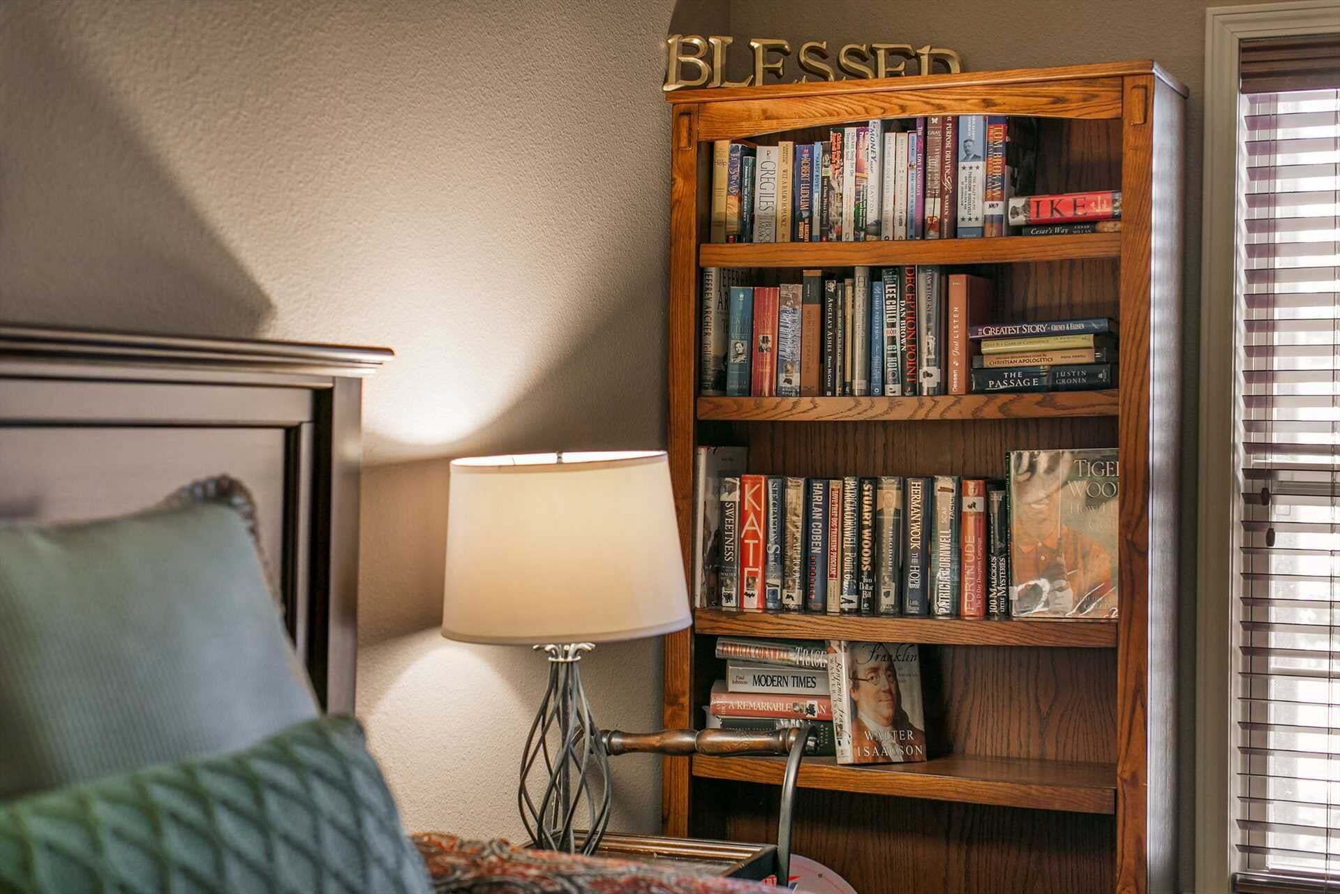 A bedroom with a wooden bookshelf, a bedside lamp, and a pillow on the bed.