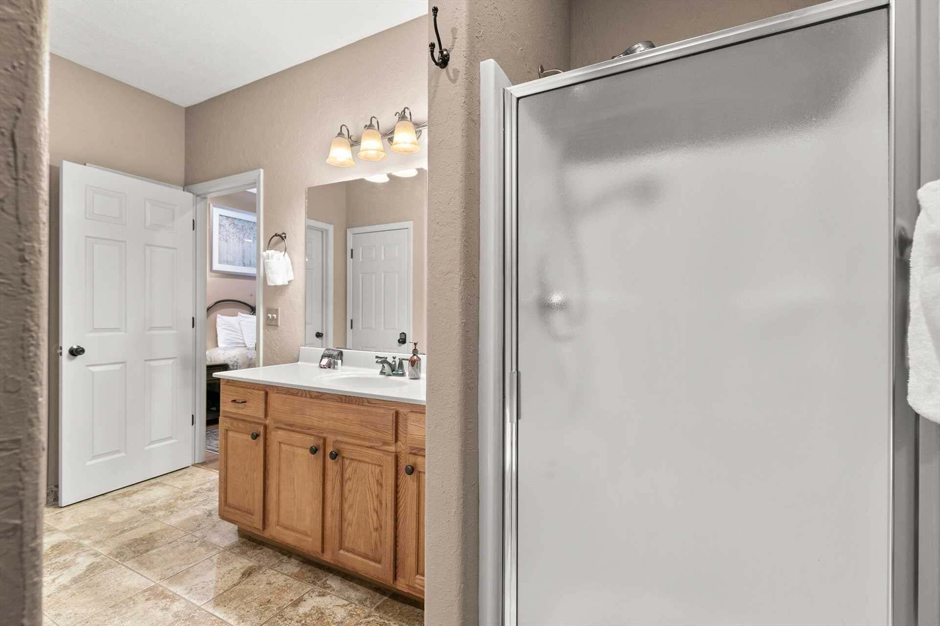 A bathroom with a white door, a double sink vanity, and a mirror above the sink.