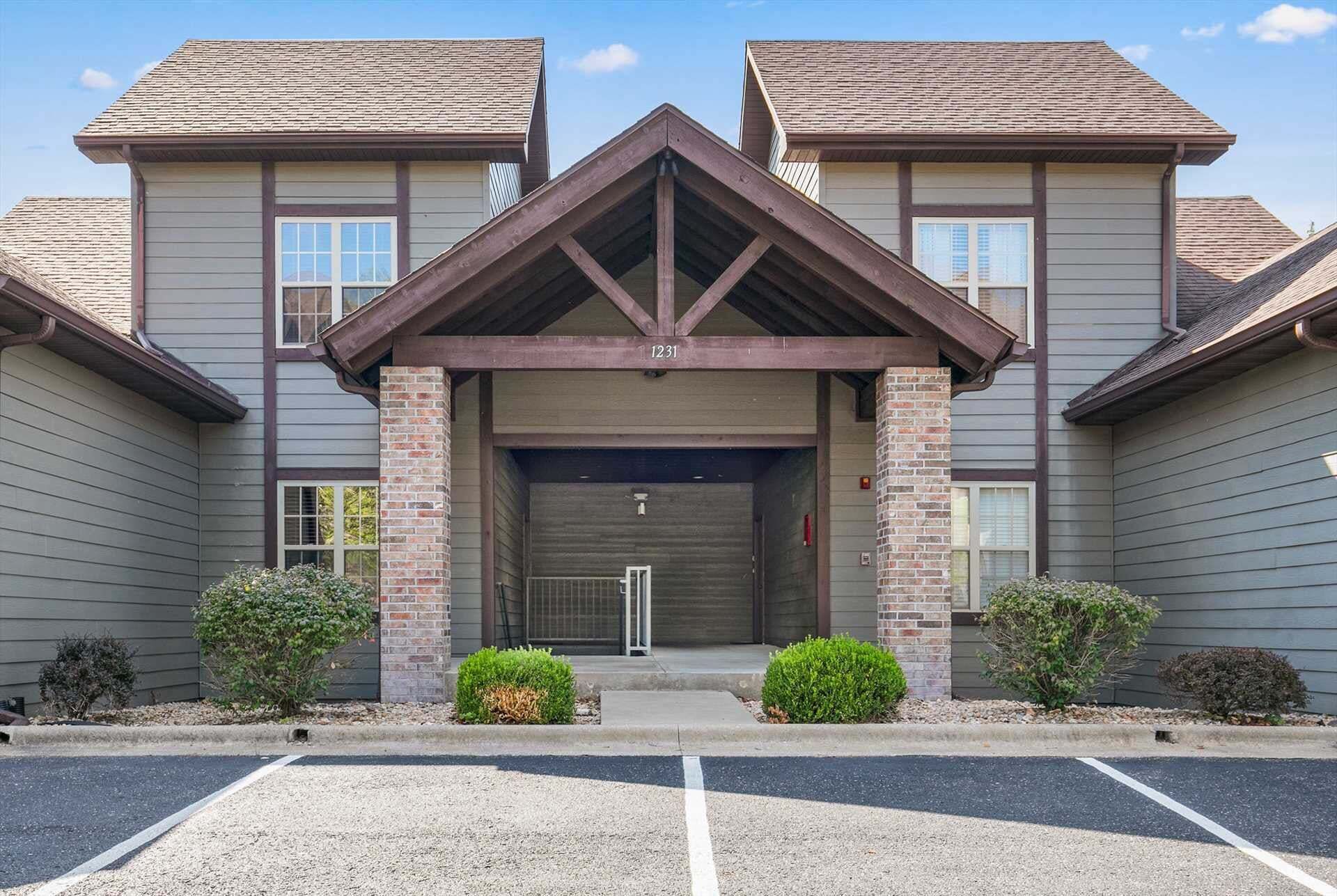 A building with a central entrance, brick pillars, and a garage door.