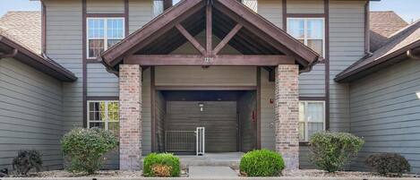 A building with a central entrance, brick pillars, and a garage door.