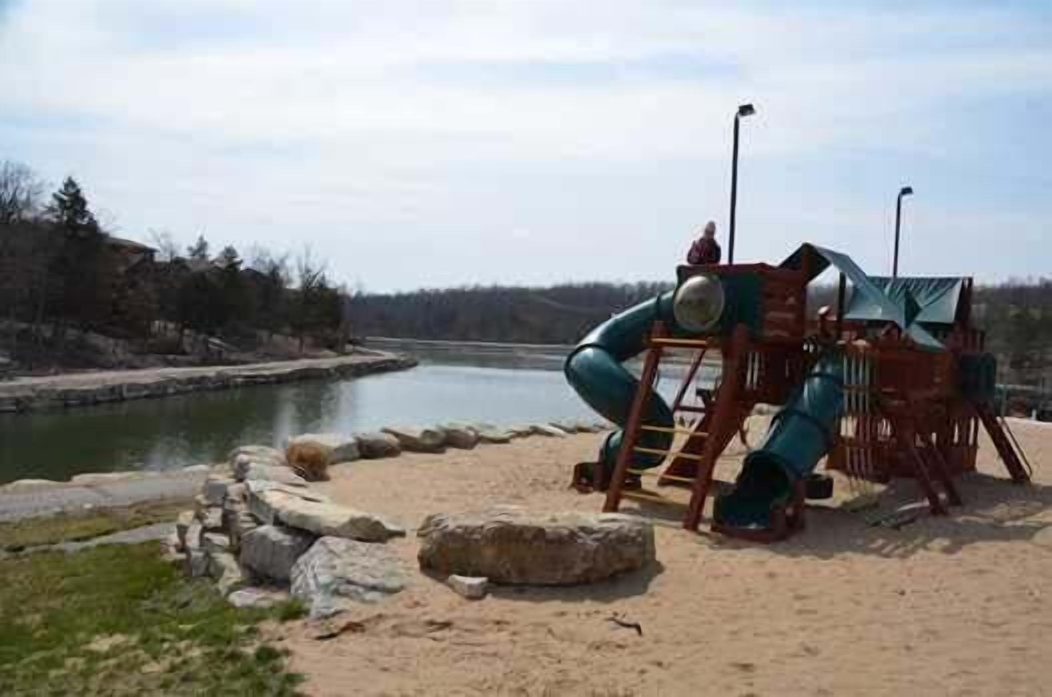 A playground with a slide and climbing structures near a body of water.