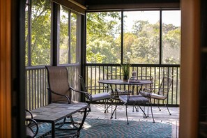 A covered outdoor seating area with metal chairs and a table, overlooking a wooded area. - Beautiful Golf Course view, Near SDC, Lots of Space, Free Daily Attraction Tickets (Branson West)