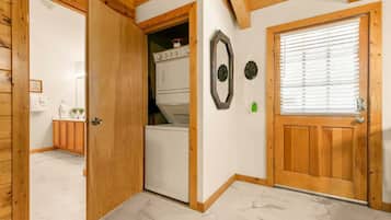 Un intérieur en bois avec une porte donnant sur une buanderie, un miroir et une fenêtre avec des stores.