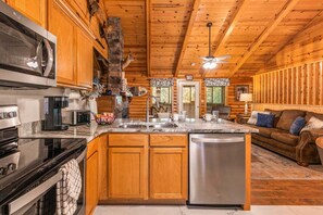 A cabin interior with a kitchen, dining area, and living room. - Free Daily Attraction Tickets, Four King Rooms, Huge Sunroom, Shared Arcades (Branson)